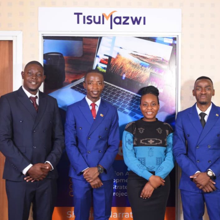 The four-member TisuMazwi team photographed together in front of the TisuMazwi banner.